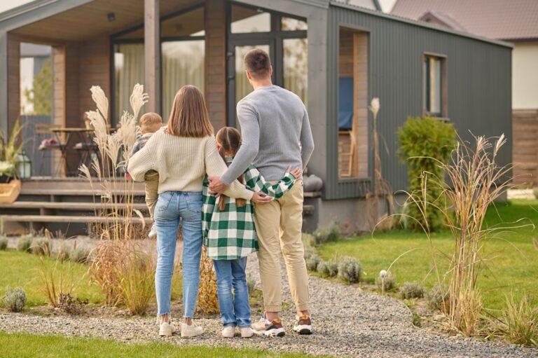 back-view-family-hugging-admiring-their-home