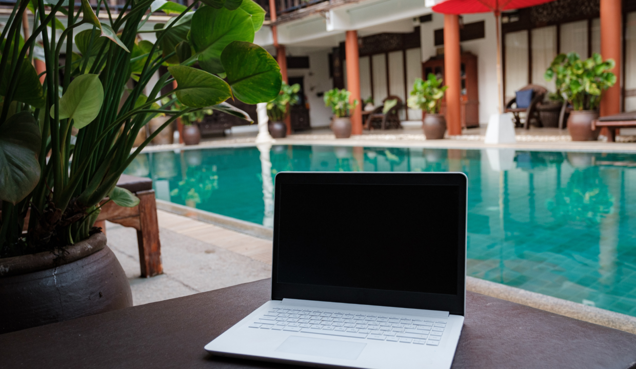 A laptop placed near a serene poolside in Bali, symbolizing the rise of digital nomad-friendly accommodations in Bali’s real estate trends.