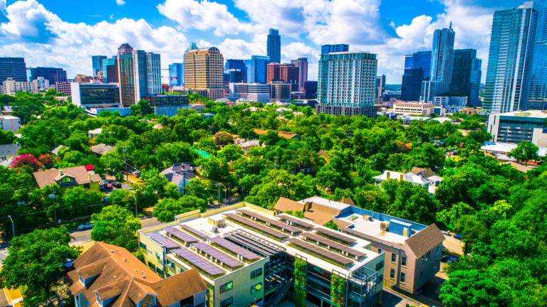 A vibrant aerial view of a cityscape showcasing green property development, with lush trees and solar-panelled buildings.