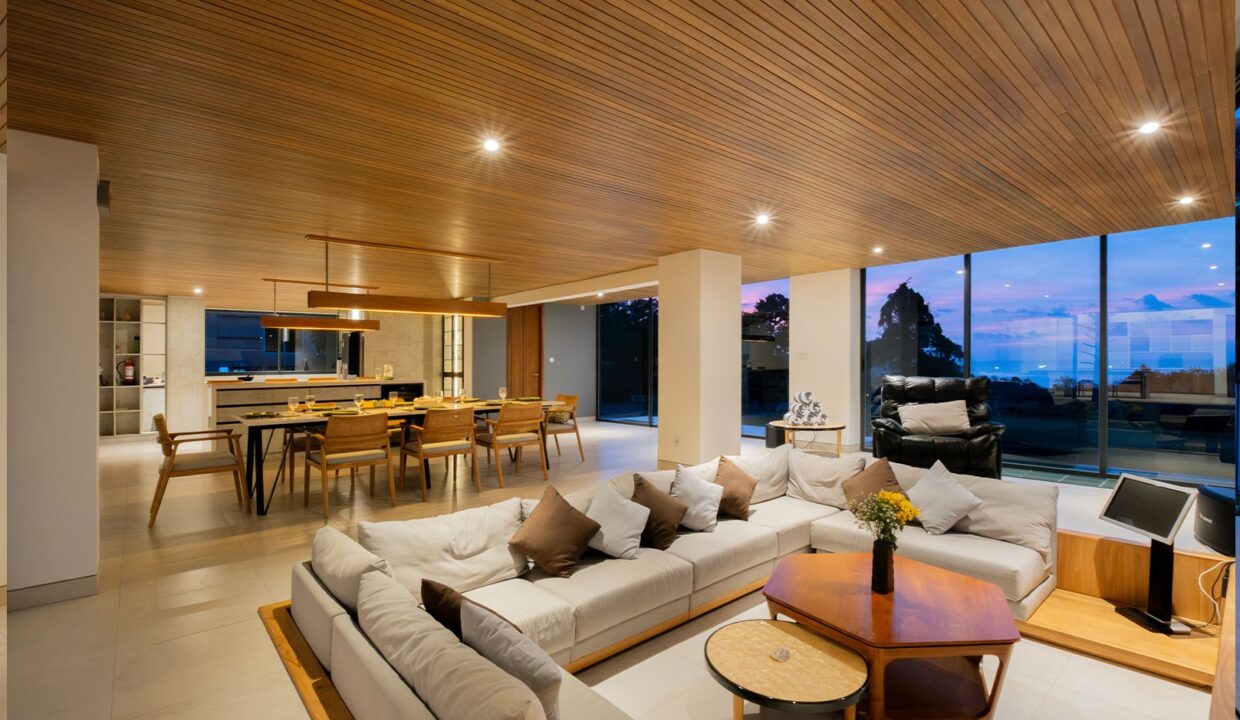 Spacious living and dining area in a luxury Uluwatu villa with ocean views, modern furnishings, and sunset backdrop.