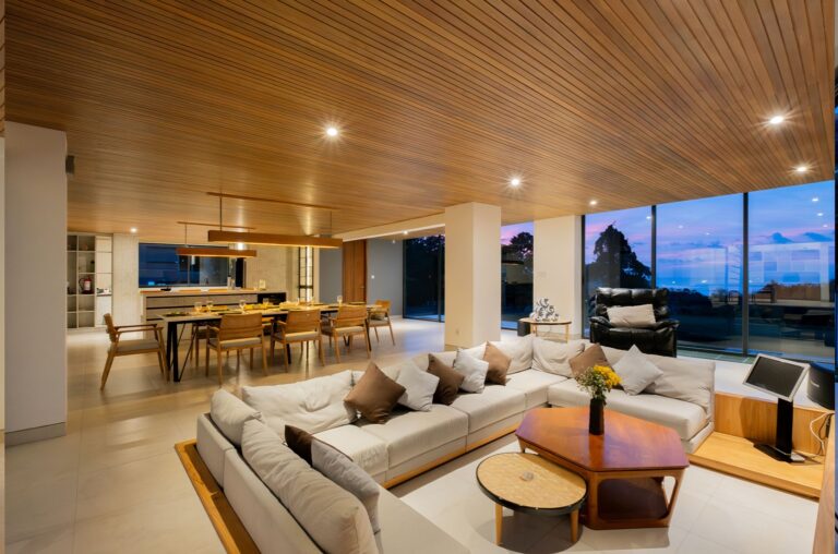 Spacious living and dining area in a luxury Uluwatu villa with ocean views, modern furnishings, and sunset backdrop.