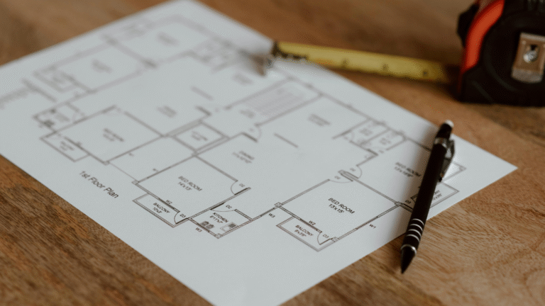 Off-Plan Property Illustration by floor plan layout on a wooden table with pen and measuring tape.