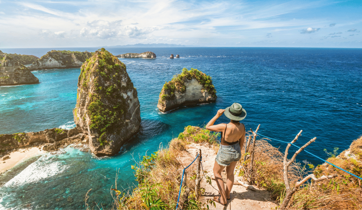 A first-time traveler overlooking the dramatic cliffs and turquoise waters of Nusa Penida — a must-see destination when deciding what to do in Bali.