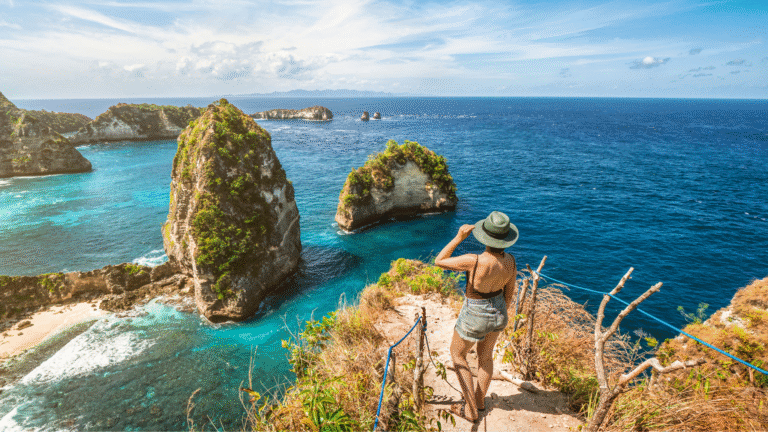 A first-time traveler overlooking the dramatic cliffs and turquoise waters of Nusa Penida — a must-see destination when deciding what to do in Bali.