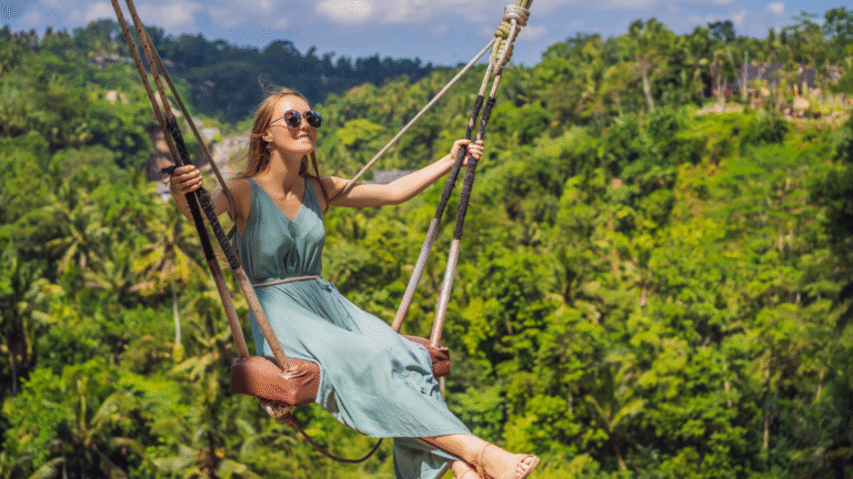 A woman enjoys a thrilling ride on a giant jungle swing in Bali, Indonesia, surrounded by lush green tropical forest - one of the top outdoor activities in Bali, Indonesia.