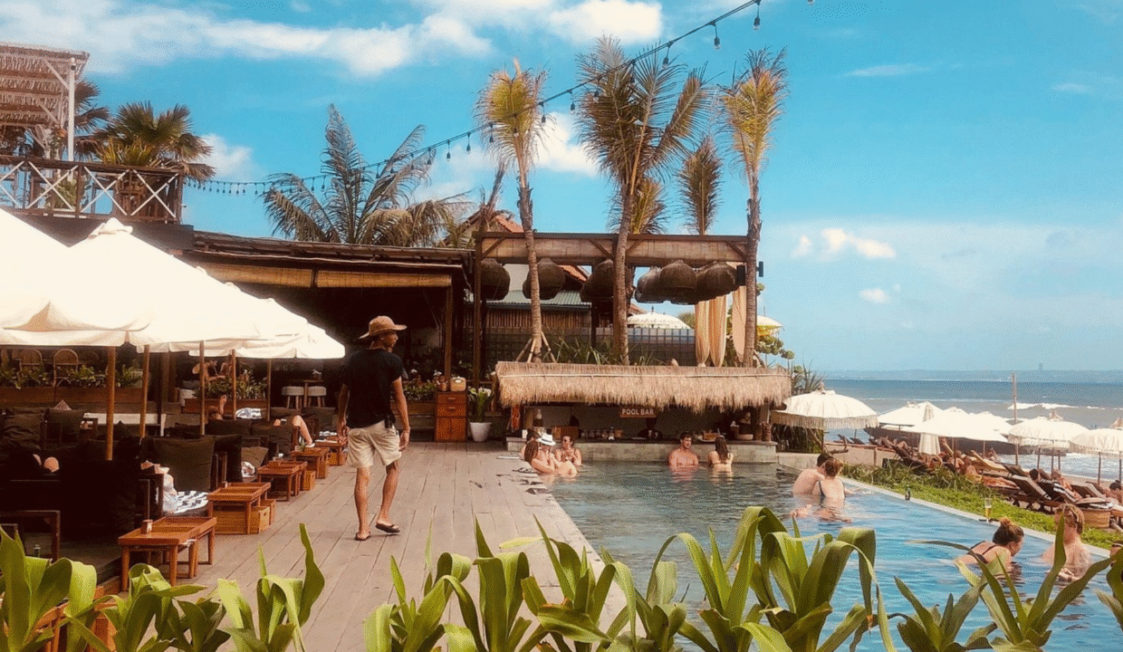 Beachgoers relaxing at a stylish pool bar with ocean views in Canggu, Bali, a perfect example of what to do in Canggu for sun, surf, and social vibes.