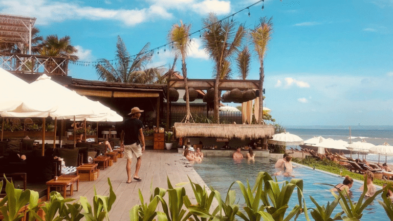 Beachgoers relaxing at a stylish pool bar with ocean views in Canggu, Bali, a perfect example of what to do in Canggu for sun, surf, and social vibes.