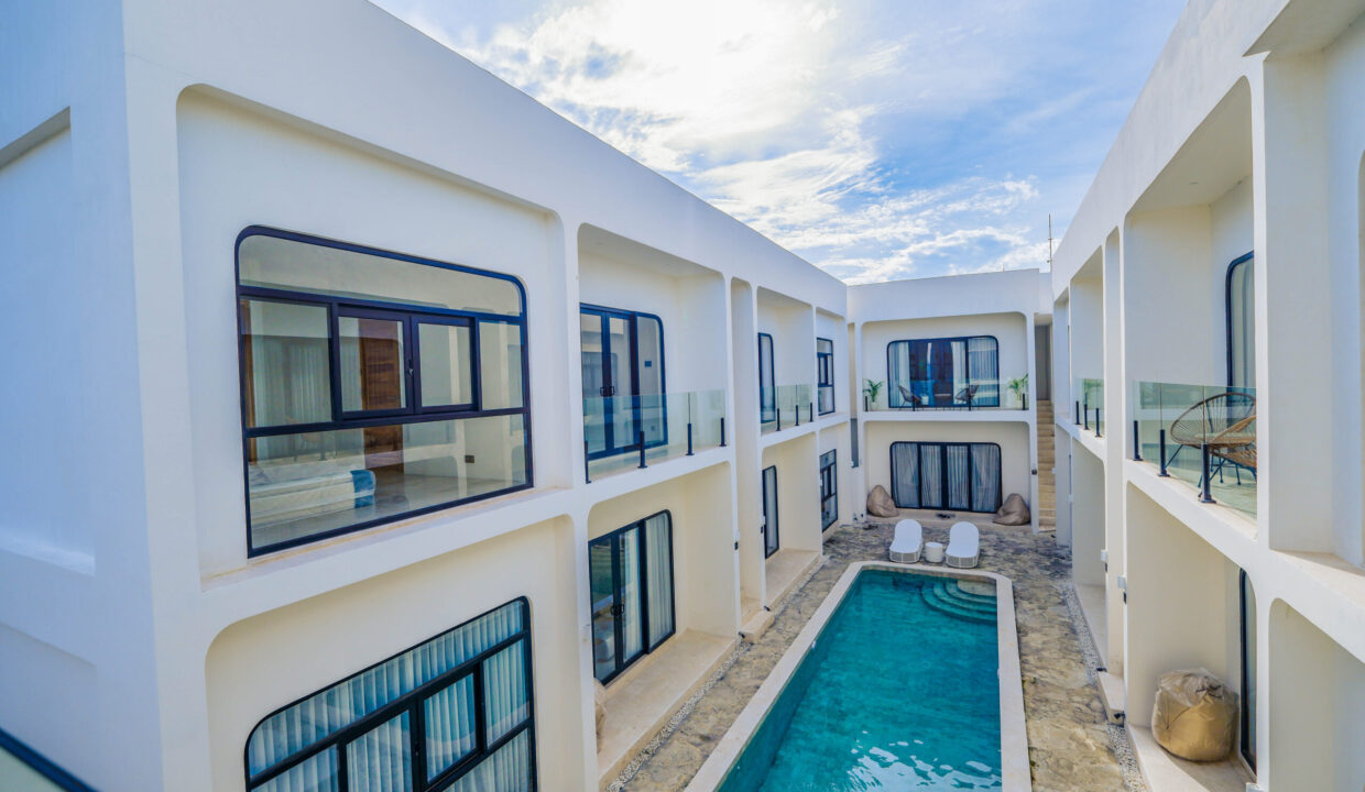 Modern Bali apartment complex with poolside view, featuring contemporary design, large windows, and private balconies.