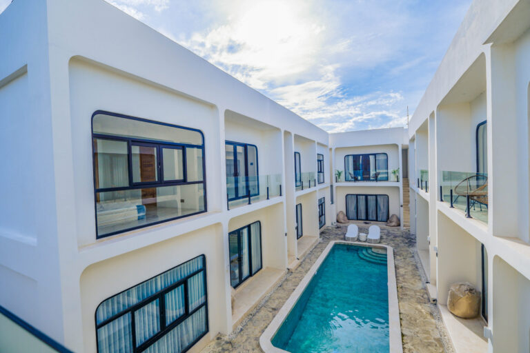 Modern Bali apartment complex with poolside view, featuring contemporary design, large windows, and private balconies.
