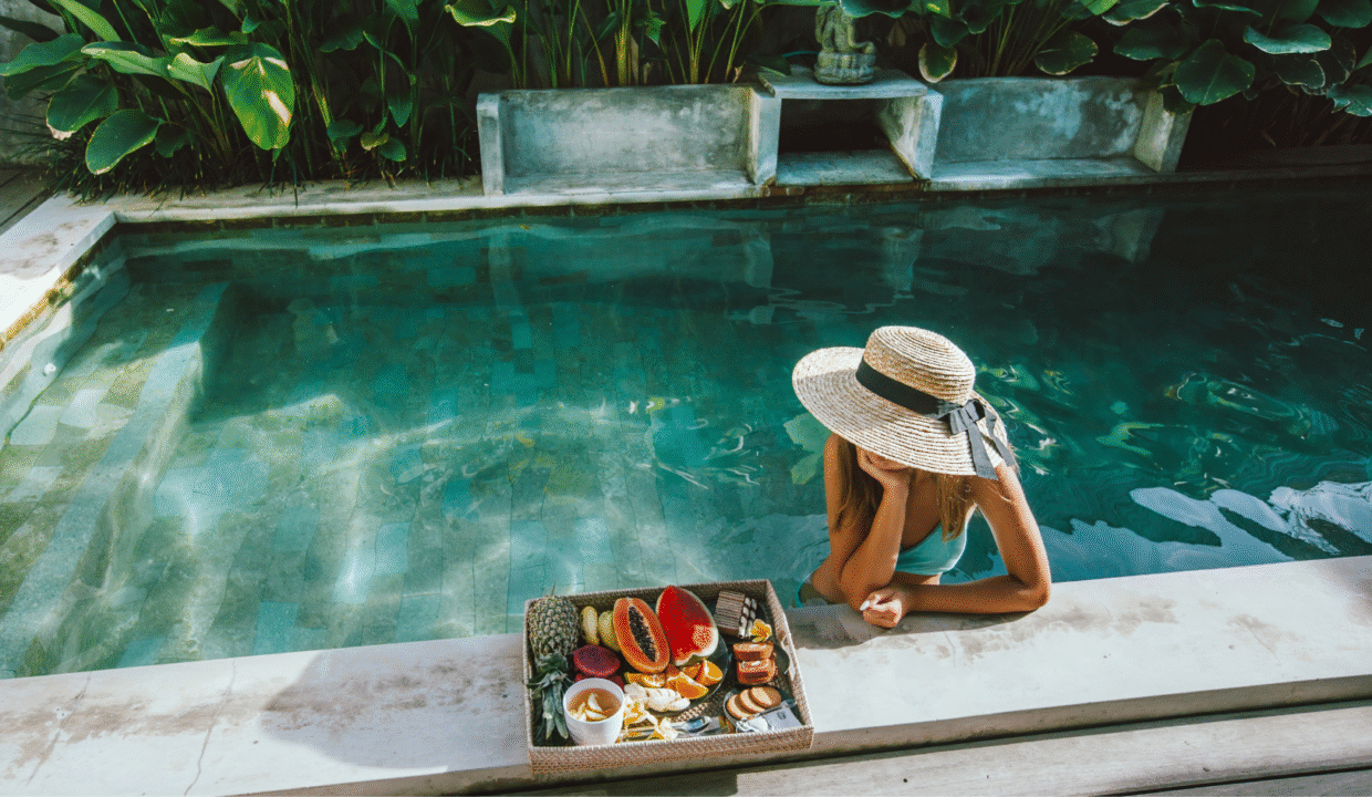 A woman relaxing by a private pool with tropical fruit breakfast at a luxury villa — representing the comfort and lifestyle of a long-term villa rental in Bali.