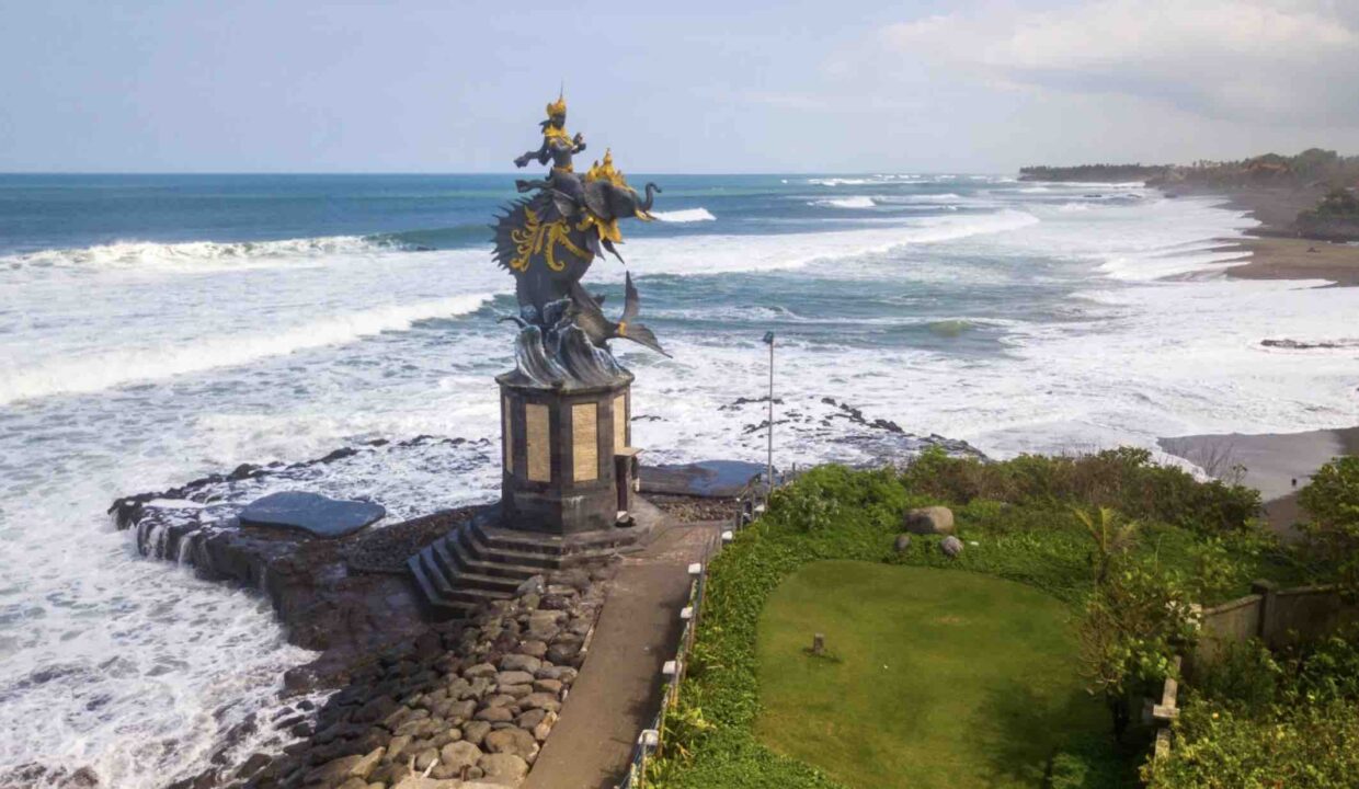 Ocean view of Pererenan Beach in Bali featuring a seaside statue, showcasing the scenic appeal that enhances Pererenan property investment opportunities.