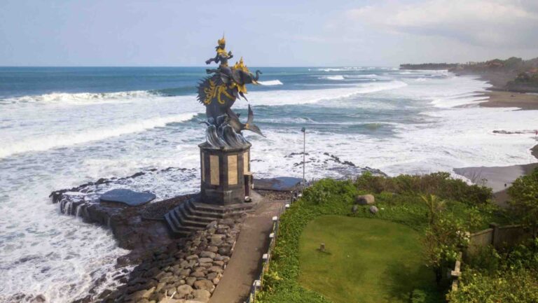 Ocean view of Pererenan Beach in Bali featuring a seaside statue, showcasing the scenic appeal that enhances Pererenan property investment opportunities.