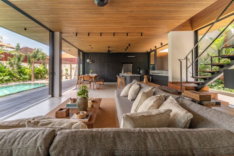 A spacious open-plan living area in a modern tropical home with poolside views, showcasing the comfort and style offered by family villas for rent in Bali.