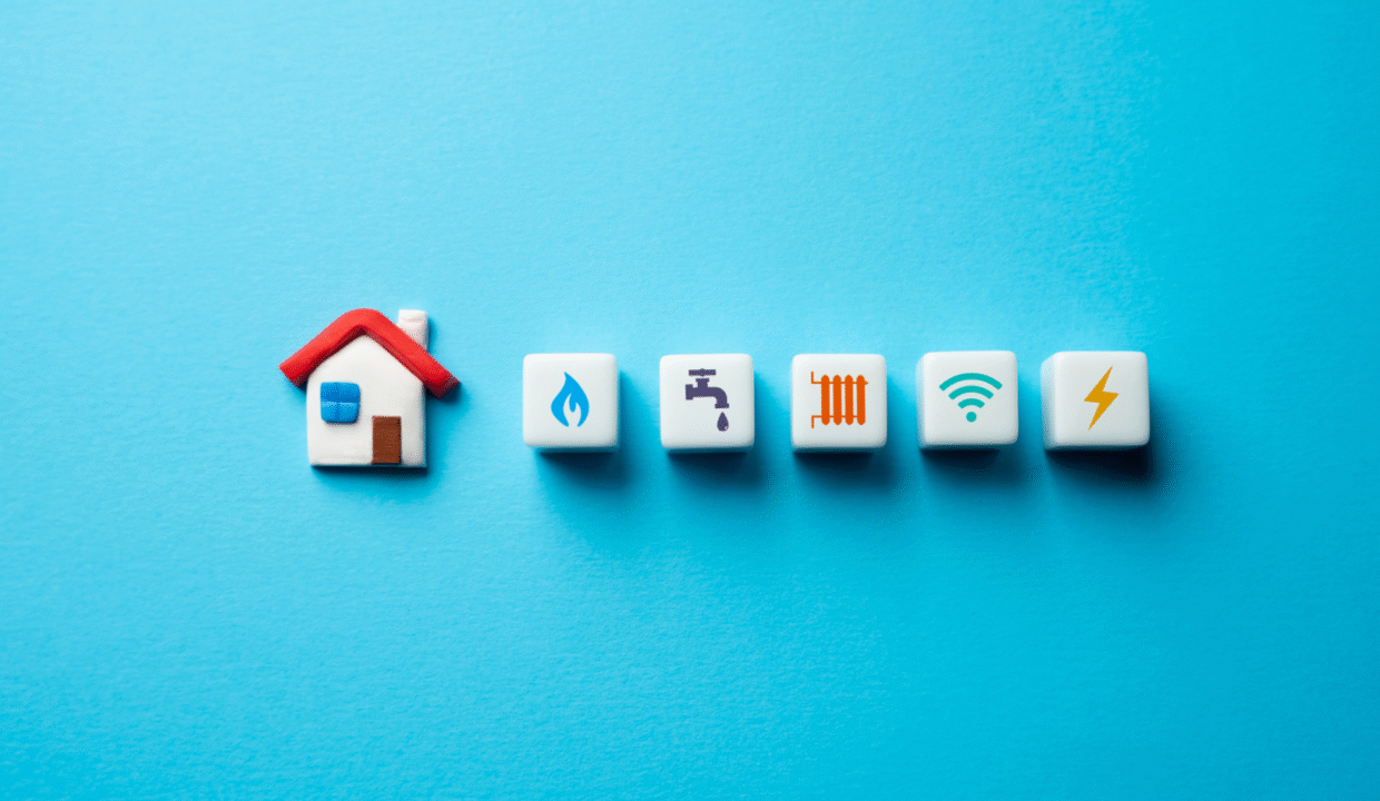 A small house icon beside symbols representing gas, water, heating, Wi-Fi, and electricity on a blue background, illustrating property utilities in Bali.