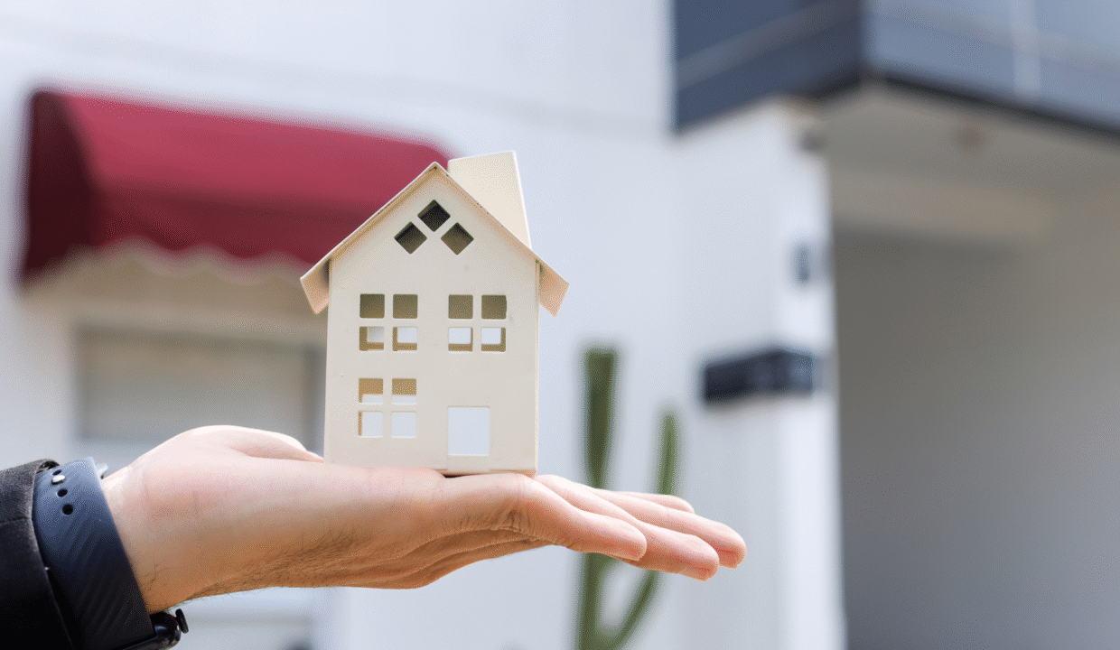 A person holding a small model house outdoors, symbolizing property ownership in Bali for Australians and real estate investment opportunities.