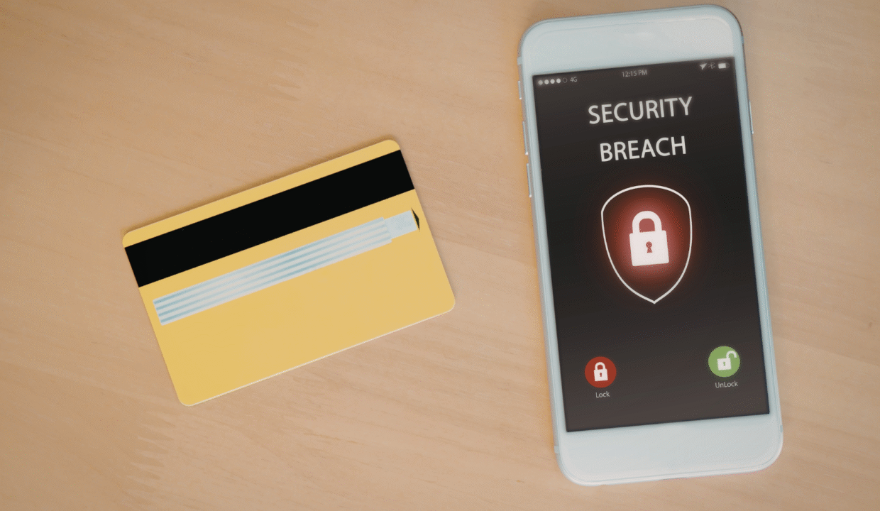 A credit card next to a phone displaying a security breach warning, illustrating the risks of card skimming in Bali.