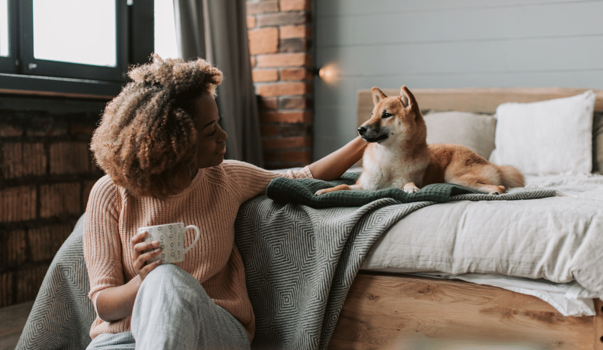 A woman relaxing indoors with her dog in a cozy bedroom, reflecting the comfort and lifestyle offered by pet-friendly villas in Bali.