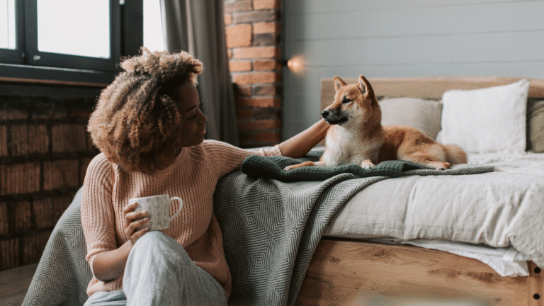 A woman relaxing indoors with her dog in a cozy bedroom, reflecting the comfort and lifestyle offered by pet-friendly villas in Bali.