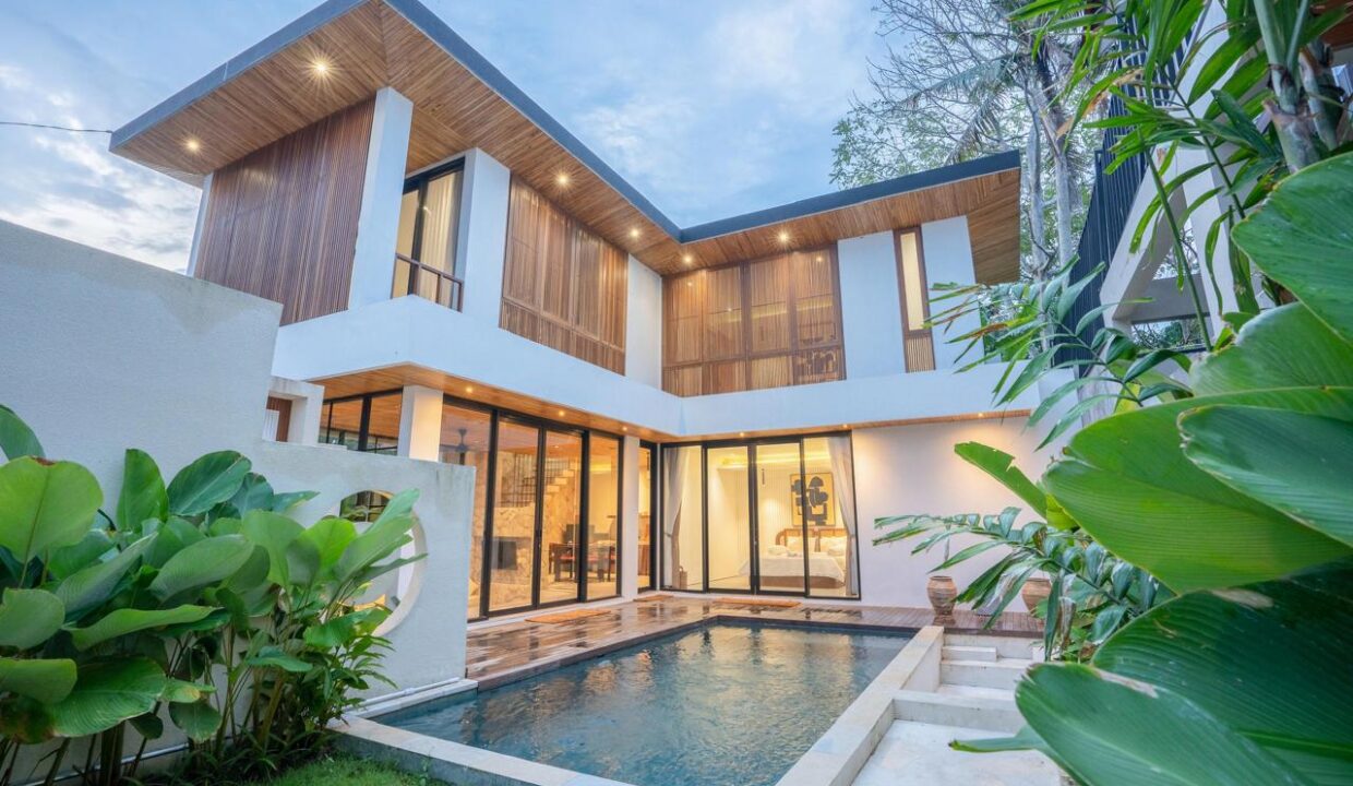 A modern tropical villa with wood accents, large windows, and a private pool, showcasing Bali villa design trends in 2026.
