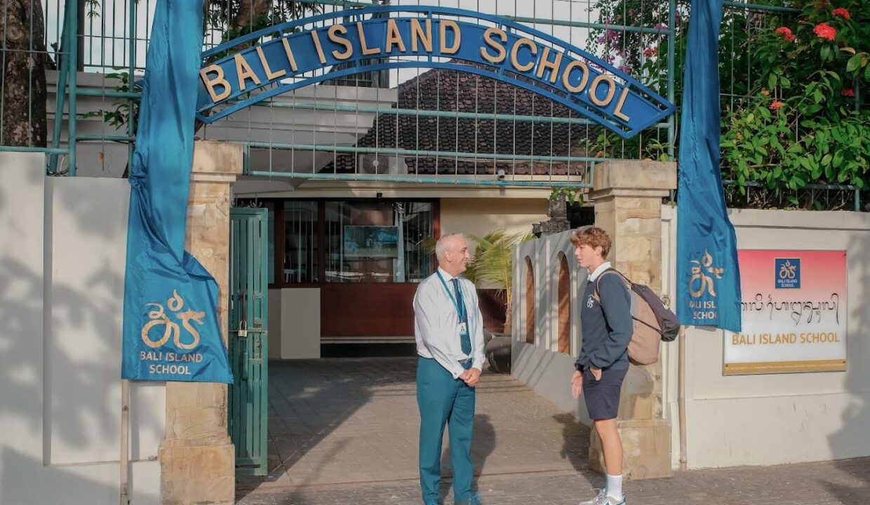 A student speaks with a teacher outside Bali Island School’s main entrance, showing a family-friendly environment near international education facilities; ideal context for villas near Bali schools.