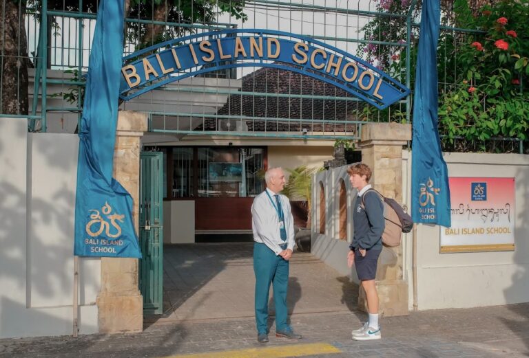 A student speaks with a teacher outside Bali Island School’s main entrance, showing a family-friendly environment near international education facilities; ideal context for villas near Bali schools.