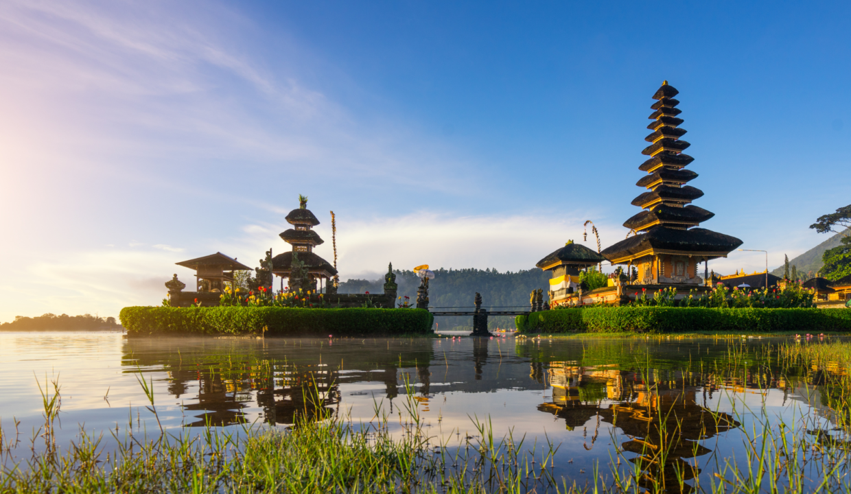 Traditional Balinese temple complex by a lake at sunrise, reflecting Bali’s cultural appeal and its influence on land price in Bali.