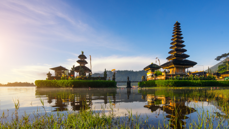 Traditional Balinese temple complex by a lake at sunrise, reflecting Bali’s cultural appeal and its influence on land price in Bali.