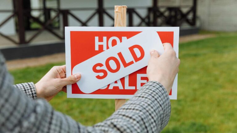 A buyer places a sold sign on a home for sale, symbolizing successful real estate transactions and interest to buy property in Ubud.