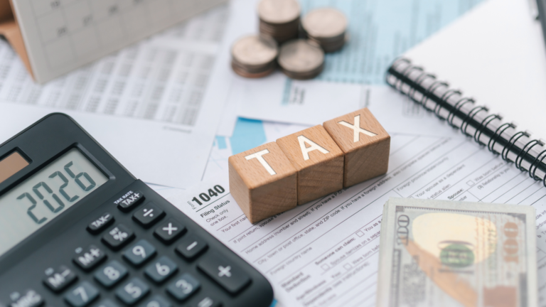 Property sales tax concept illustrated with tax documents, calculator, cash, and wooden blocks spelling tax on a financial desk.