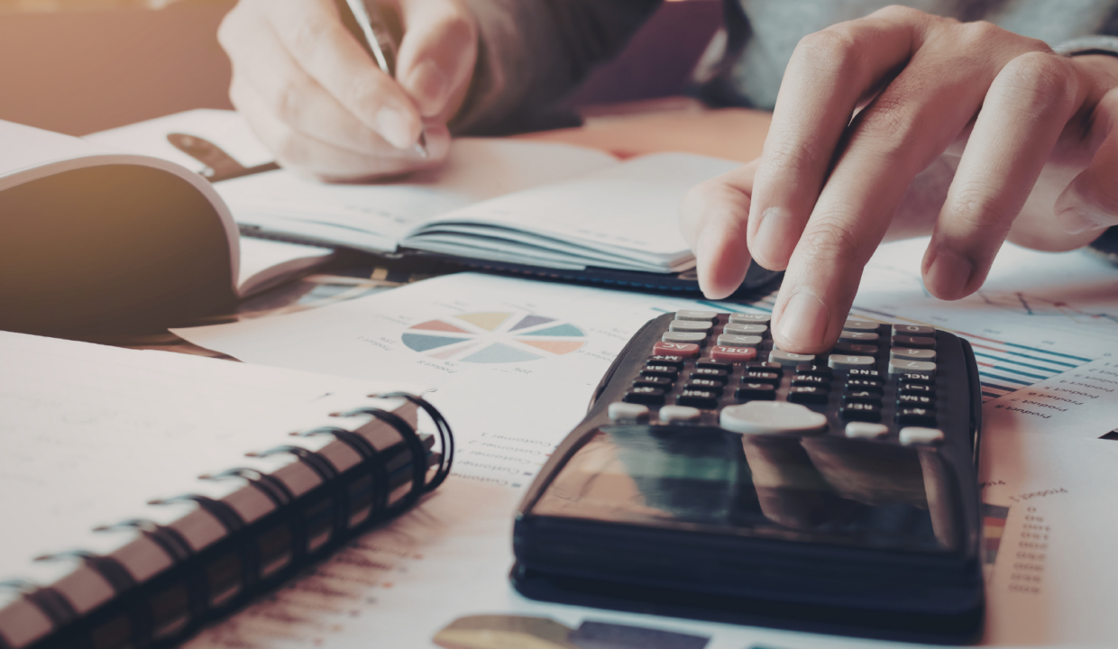 Hands using a calculator and financial reports to perform villa rental business calculations in Bali for foreign property investors.